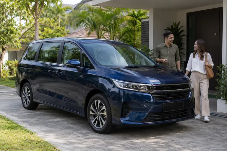 Stationary MPV in a residential driveway. Illustrative customer context.
